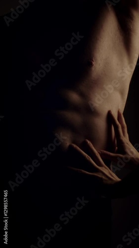 Female hands touching male's fit torso with passion. Slow motion. Vertical orientation