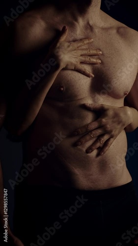 Female hands touching male's fit torso with passion. Slow motion. Vertical orientation
