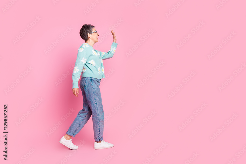 Elderly woman in stylish pastel attire walking cheerfully against a vibrant pink background Elderly woman in stylish pastel attire walking cheerfully against a vibrant pink background