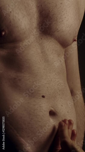 Female hands touching male's fit torso with passion. Slow motion. Vertical orientation