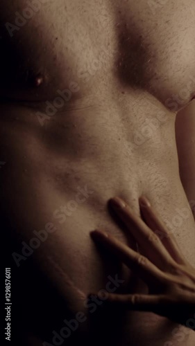 Female hands touching male's fit torso with passion. Slow motion. Vertical orientation