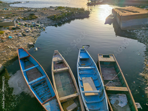 Fotografia Sunset Over Moored Boats Amidst Pollution