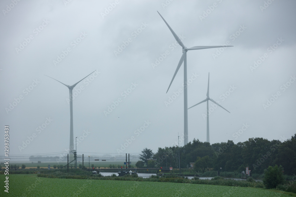 Fototapeta premium Wind turbines stand tall against the cloudy sky in rural Nederland during an overcast day