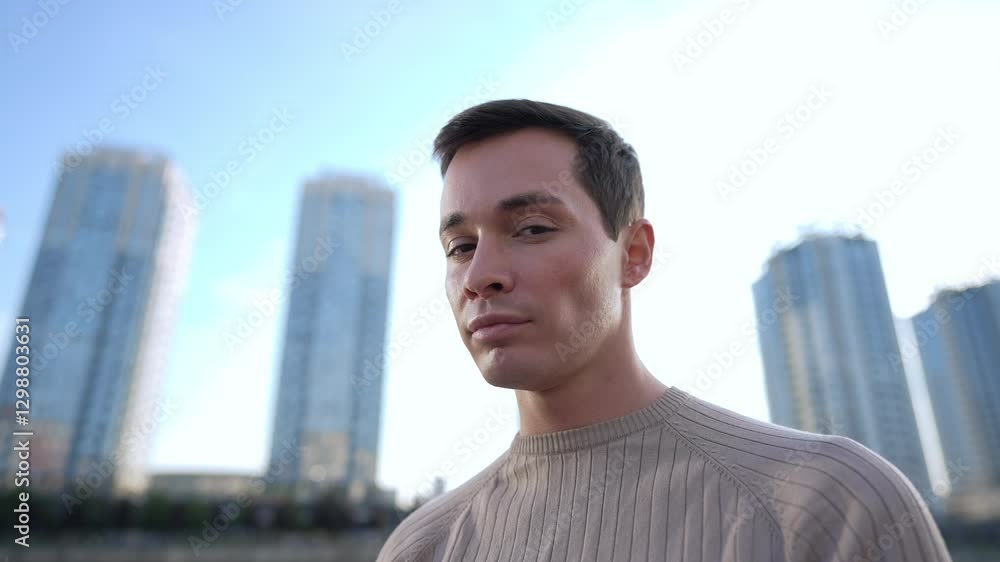 A thoughtful young man stands contemplatively in front of towering modern skyscrapers, reflecting deeply on urban life A thoughtful young man stands contemplatively in front of towering modern skyscrapers, reflecting deeply on urban life