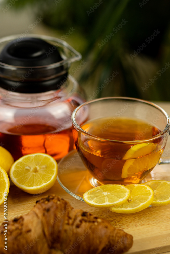 Glass cup of tea, teapot, sliced lemons on the table. Kettle with tea. Lemon tea Glass cup of tea, teapot, sliced lemons on the table. Kettle with tea. Lemon tea