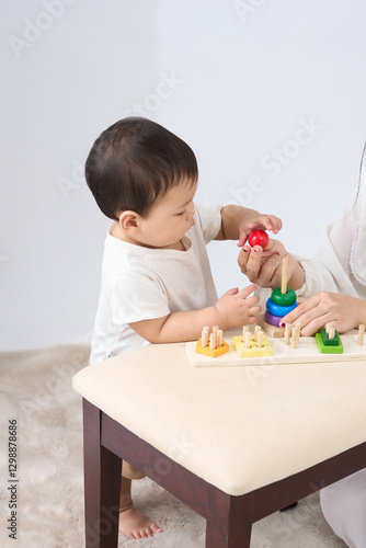 .The image shows a baby sitting at a table with toys in front of them. 
