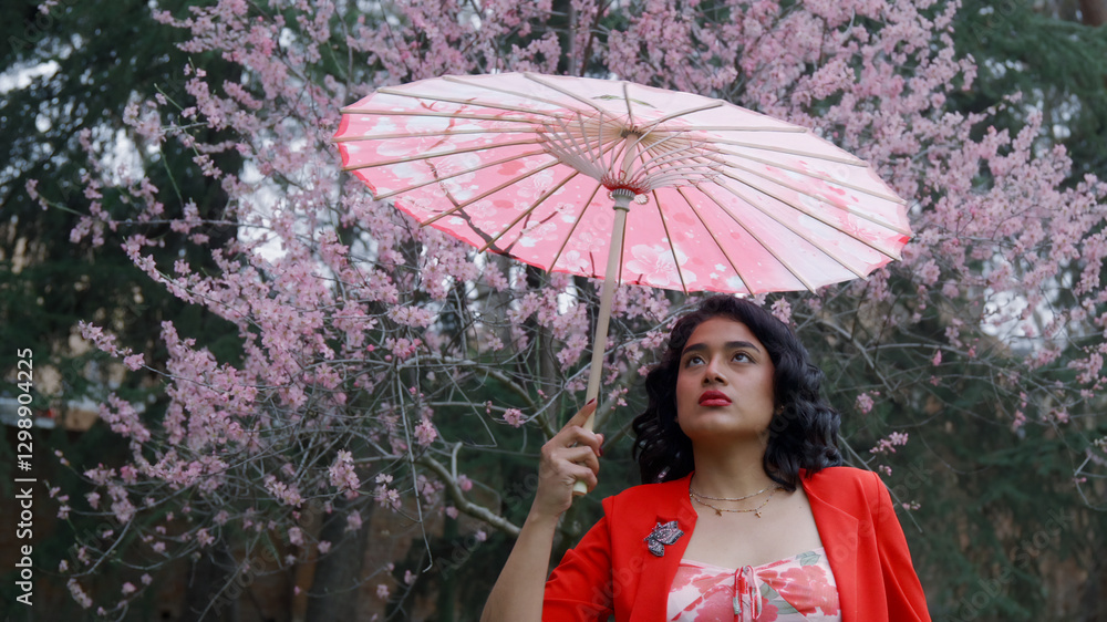 Young woman holding traditional umbrella in blooming orchard