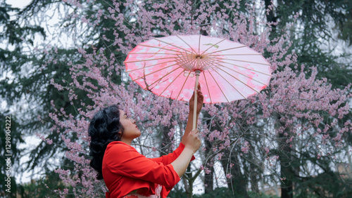Obraz na płótnie Beautiful woman holding traditional umbrella in blooming orchard w salonie