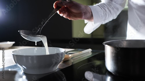 Michelin-star chef preparing a dish: Pouring milk into a saucepan, showcasing culinary expertise and attention to detail