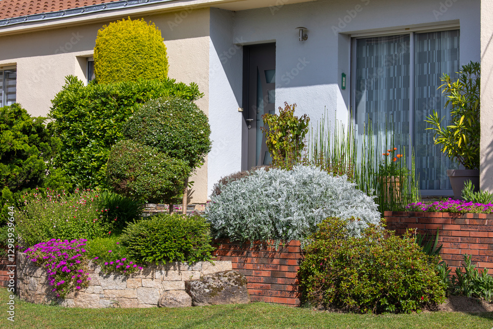 Fototapeta premium Charmant petit jardin paysagé avec ses fleurs et ses plantes vertes au printemps.