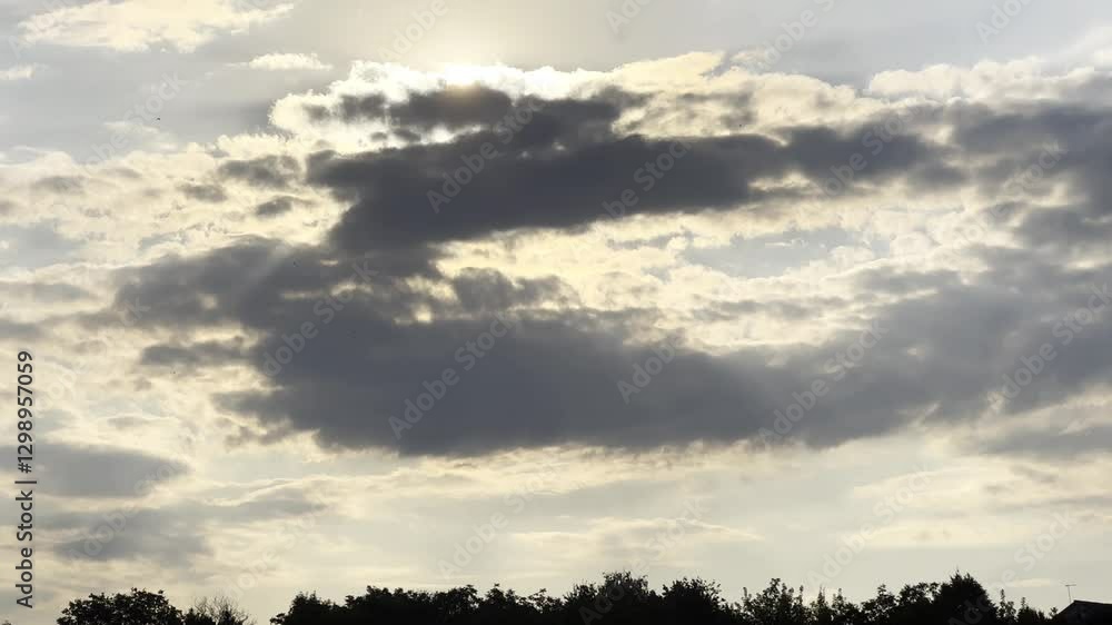 Sunlight breaking through cumulus cloud at sunset. Sun going down behind gray clouds on sky at summer day. Beautiful nature background. Close up Slow motion Sunlight breaking through cumulus cloud at sunset. Sun going down behind gray clouds on sky at summer day. Beautiful nature background. Close up Slow motion