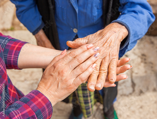 Hand einer alten Frau in der Hand einer jungen Frau