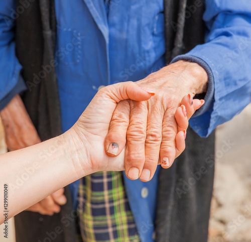 Hand einer alten Frau in der Hand einer jungen Frau