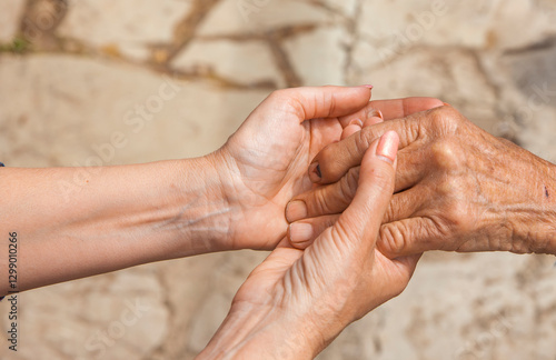 Hand einer alten Frau in der Hand einer jungen Frau