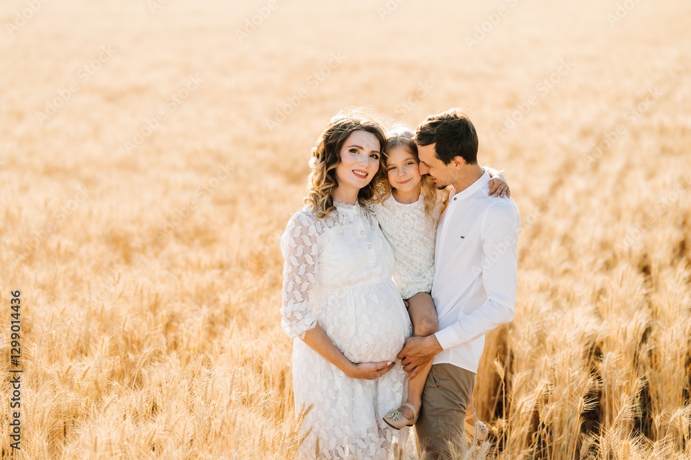A happy family is waiting for a child, a pregnant woman, a man and their daughter in a wheat field A happy family is waiting for a child, a pregnant woman, a man and their daughter in a wheat field