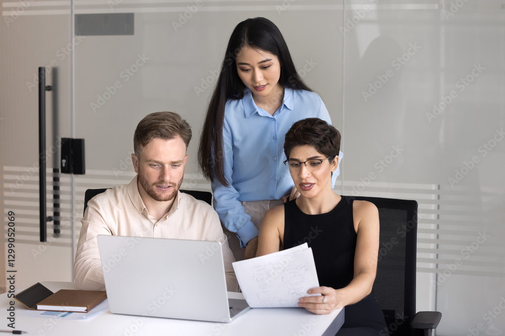 Collaborative work. Focused group three diverse multiethnic employees business team with young woman leader develop document text analyze financial report conduct research using notebook at workplace Collaborative work. Focused group three diverse multiethnic employees business team with young woman leader develop document text analyze financial report conduct research using notebook at workplace