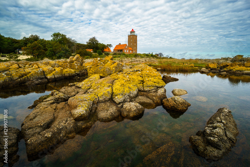 Lighthouse on rocky shore with dramatic sky, Svaneke, Bornholm, Denmark