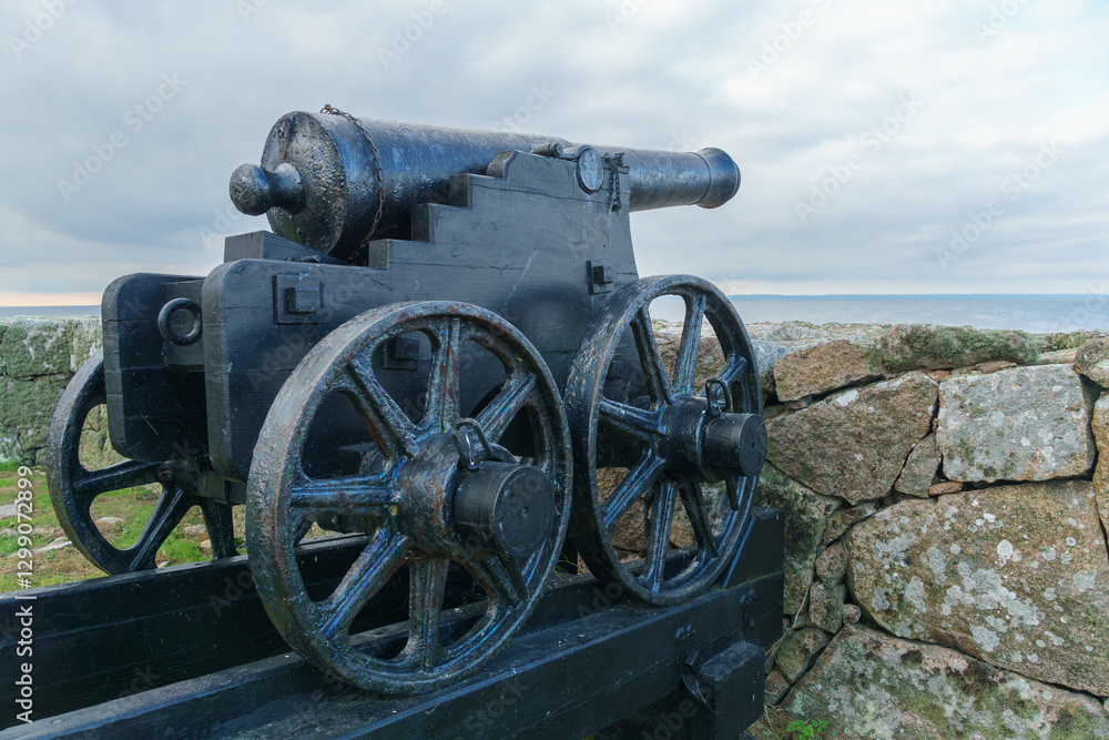 Historic cannon next to stone wall by the sea. Christiansø, Bornholm, Denmark Historic cannon next to stone wall by the sea. Christiansø, Bornholm, Denmark