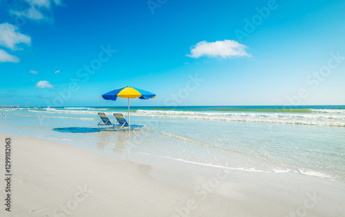 Two beach chairs and a colorful parasol on the sand