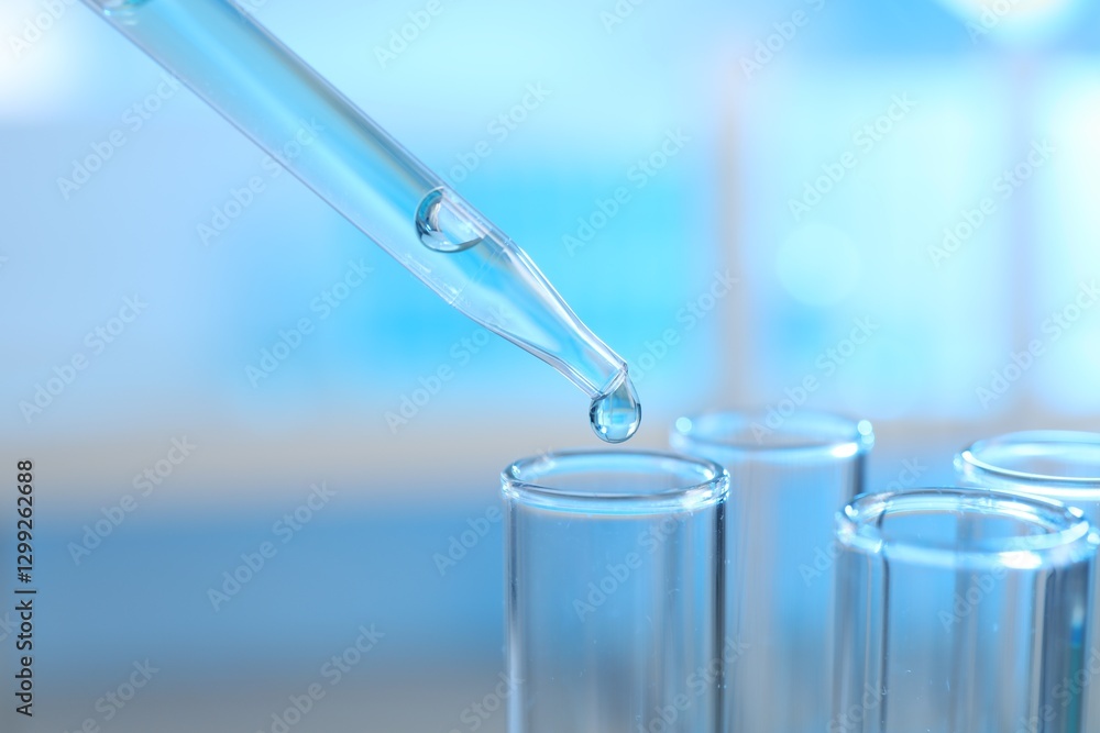 Dripping liquid into test tubes on light background, closeup Dripping liquid into test tubes on light background, closeup