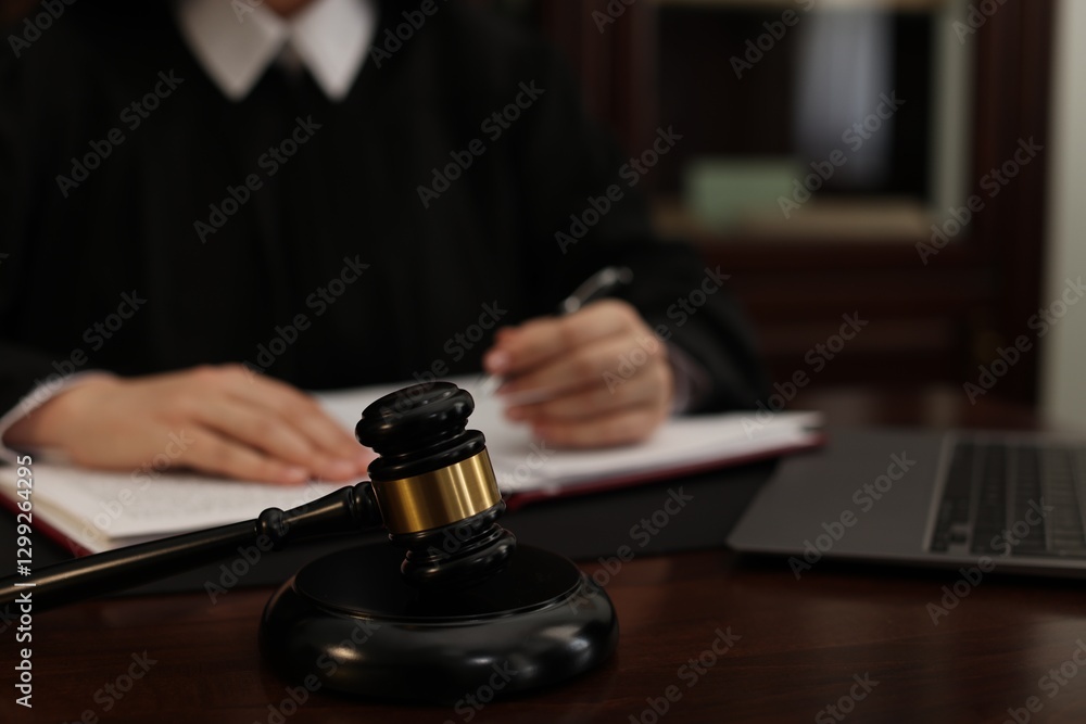 Judge working at wooden table in office, focus on gavel Judge working at wooden table in office, focus on gavel