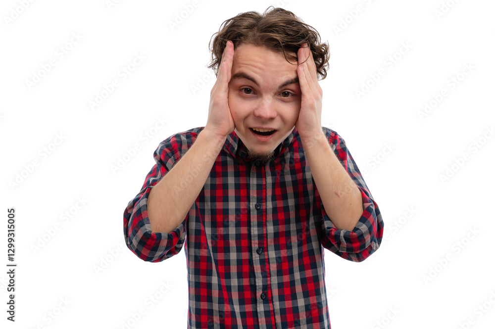 A young man with curly hair expressing surprise while holding his head with both hands against a white background. A young man with curly hair expressing surprise while holding his head with both hands against a white background.