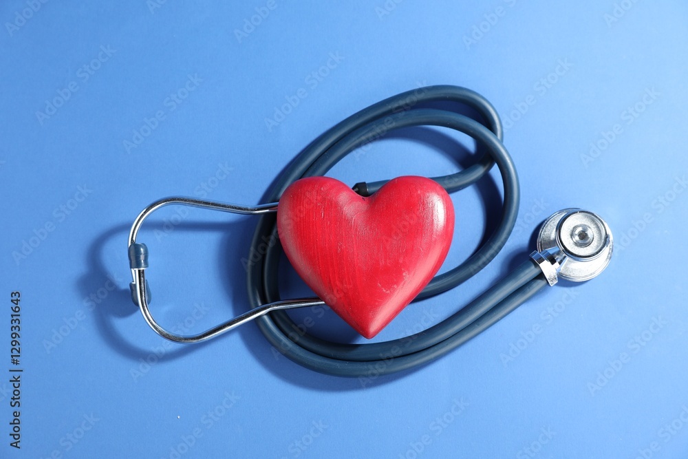 Stethoscope and red decorative heart on blue background, top view Stethoscope and red decorative heart on blue background, top view