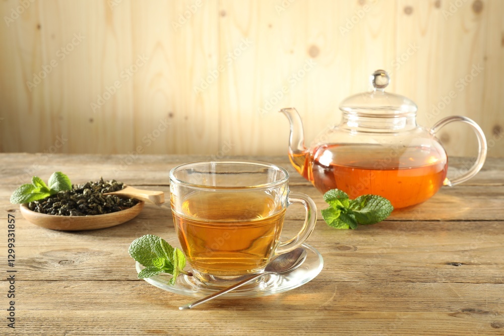 Freshly brewed tea in glass cup and teapot on wooden table