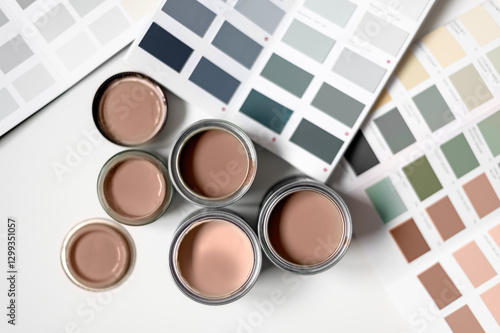 Tiny sample paint cans during house renovation, process of choosing paint for the walls, Mocha Mousse color of the year 2025, color charts on background