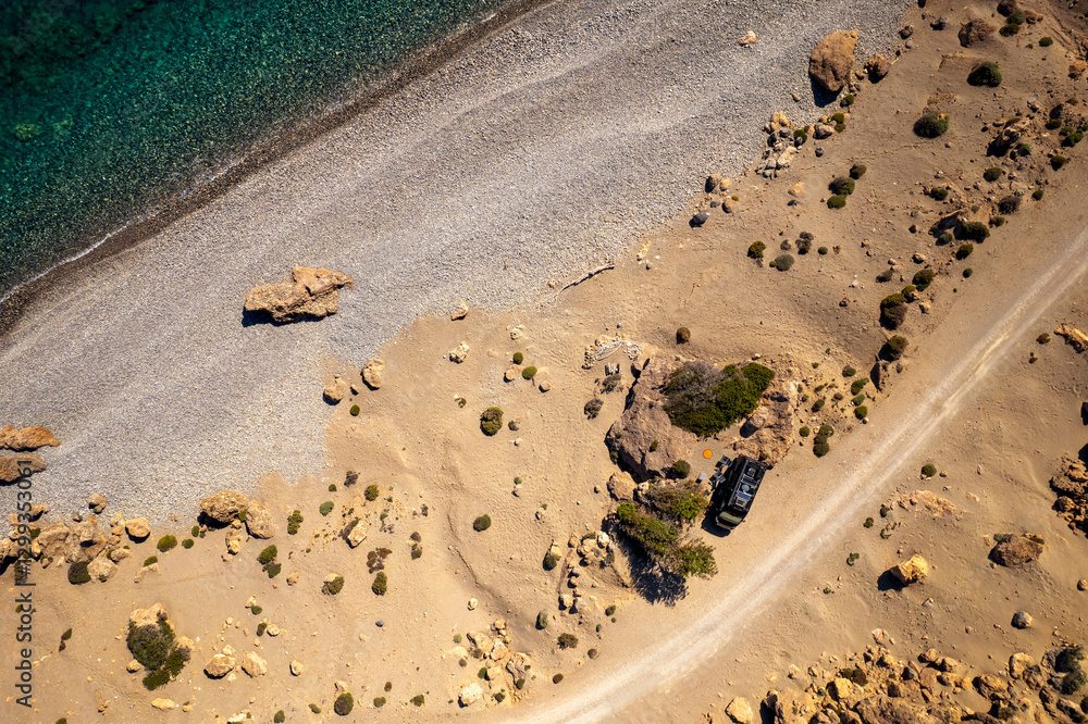 Obraz premium Aerial drone photo of black campervan wild camping at the roadside at a beach at Crete, Greece