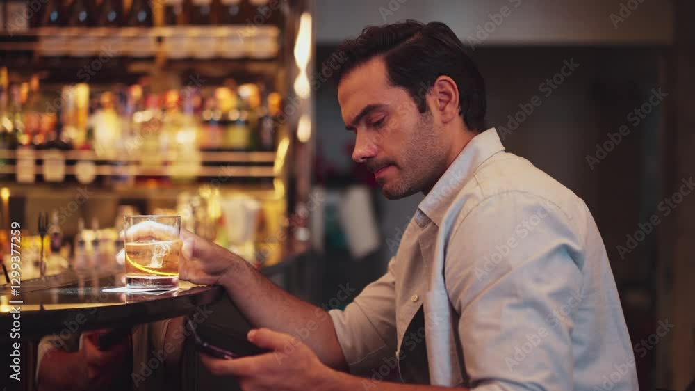 Smart man drinking cocktail in Old fashioned alone while waiting friends or couple in chatting on smartphone at counter bar at nightclub Friday meeting night at luxurious pub and restaurant. Vinosity. Smart man drinking cocktail in Old fashioned alone while waiting friends or couple in chatting on smartphone at counter bar at nightclub Friday meeting night at luxurious pub and restaurant. Vinosity.