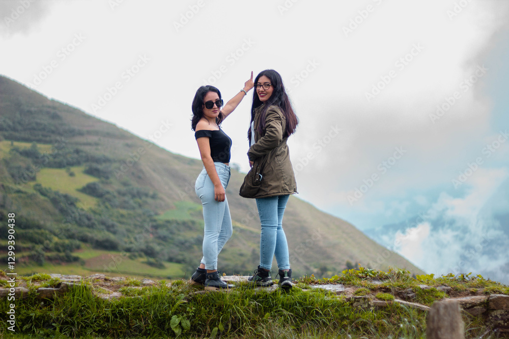 Obraz premium Dos jóvenes aventureras disfrutando la naturaleza en un día nublado.Turistas bien abrigadas en un paisaje natural bajo el cielo nublado