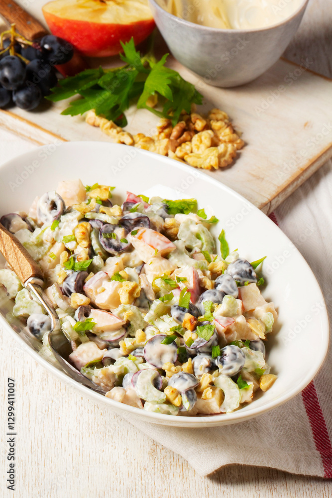 Waldorf salad with apples, celery, grapes and walnuts, dressed with mayonnaise and sprinkled with parsley.