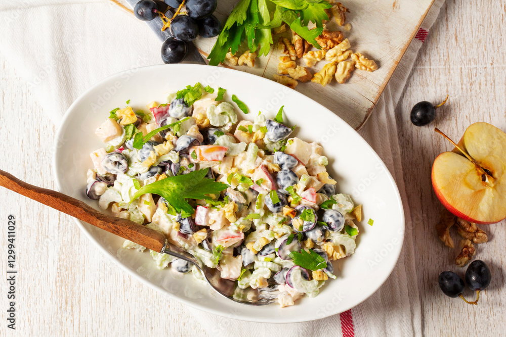 Waldorf salad with apples, celery, grapes and walnuts, dressed with mayonnaise and sprinkled with parsley.