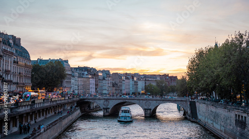 Obraz na płótnie Lovely evening scene at the bridges over seine river in paris, with sun setting down in the distance. People and transport in direction of notre dame. w salonie