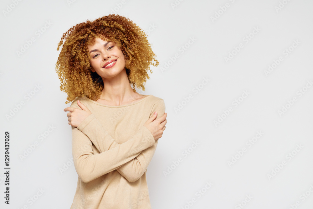 Smiling woman with curly hair embracing herself in a light beige top against a clean white background This image portrays self love and positivity in an elegant style Smiling woman with curly hair embracing herself in a light beige top against a clean white background This image portrays self love and positivity in an elegant style