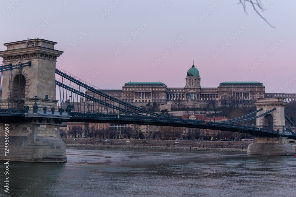 Fototapeta premium Széchenyi Chain Bridge crossing the Danube river with Buda Castle in the background during a purple sunset in Budapest