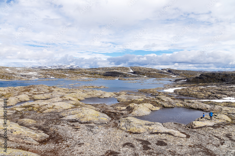 Obraz premium Breathtaking Landscape with Rocky Terrain and Serene Water Bodies in a Remote Location Under a Colorful Sky with Clouds and Snow-Capped Mountains in the Distance