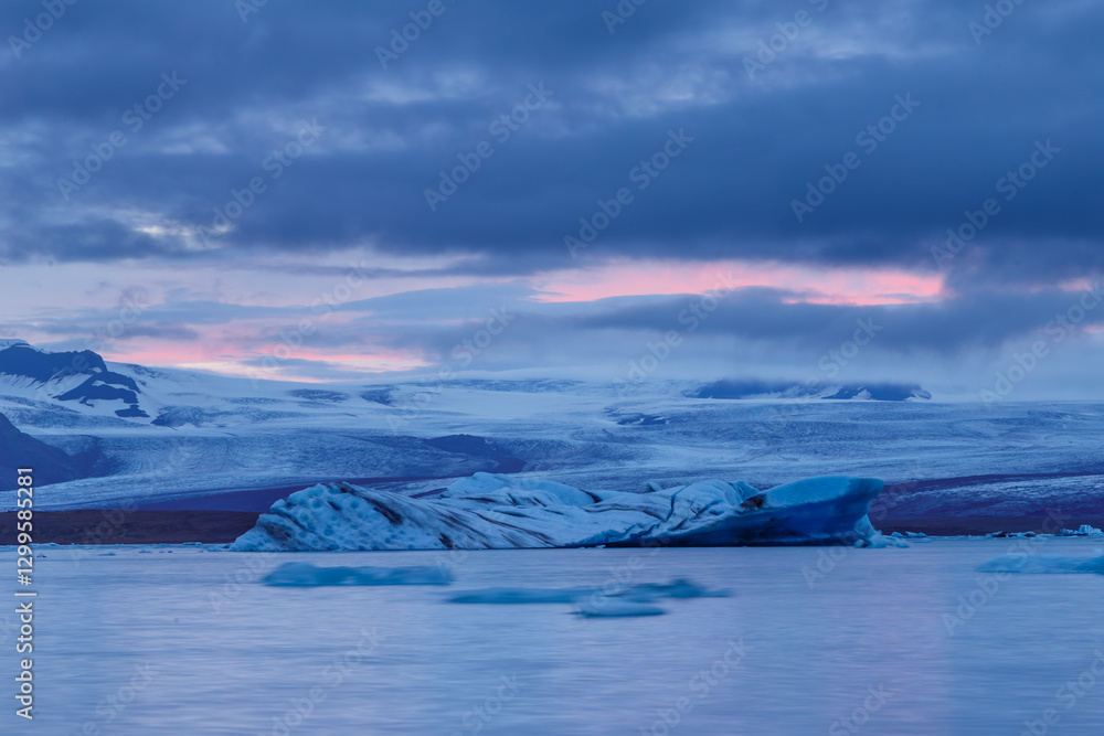 Obraz premium A Breathtaking Glacial Landscape at Dawn: Capturing the Ethereal Beauty of Icebergs and Majestic Mountains Under Dusky Skies in Iceland's Unique Wilderness