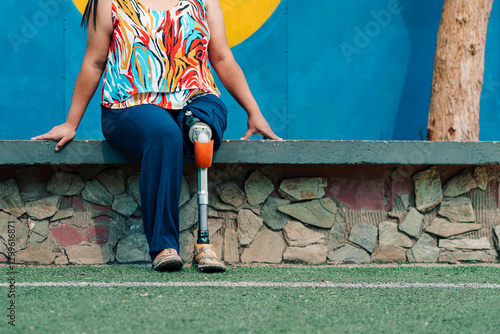 Beautiful Latina teacher with a prosthetic leg, resting and posing in the courtyard of an elementary school. She shows joy, attitude, and optimism.