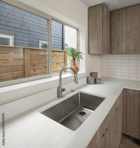 A new kitchen in a home in Portland, Oregon. Pictured is the faucet and kitchen sink next to a large window.