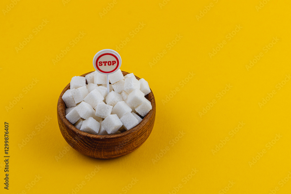 Sugar cubes in a wooden bowl with a stop sign on a bright yellow background