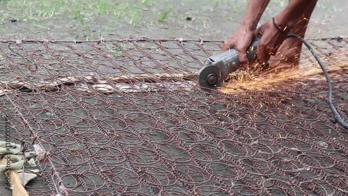 Person cutting rusty metal with an angle grinder, creating bright sparks.
