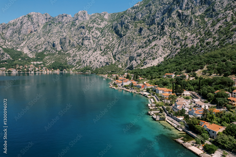 Ancient stone houses with red roofs on the shore of the Bay of Kotor at the foot of the mountains. Orahovac, Montenegro. Drone Ancient stone houses with red roofs on the shore of the Bay of Kotor at the foot of the mountains. Orahovac, Montenegro. Drone