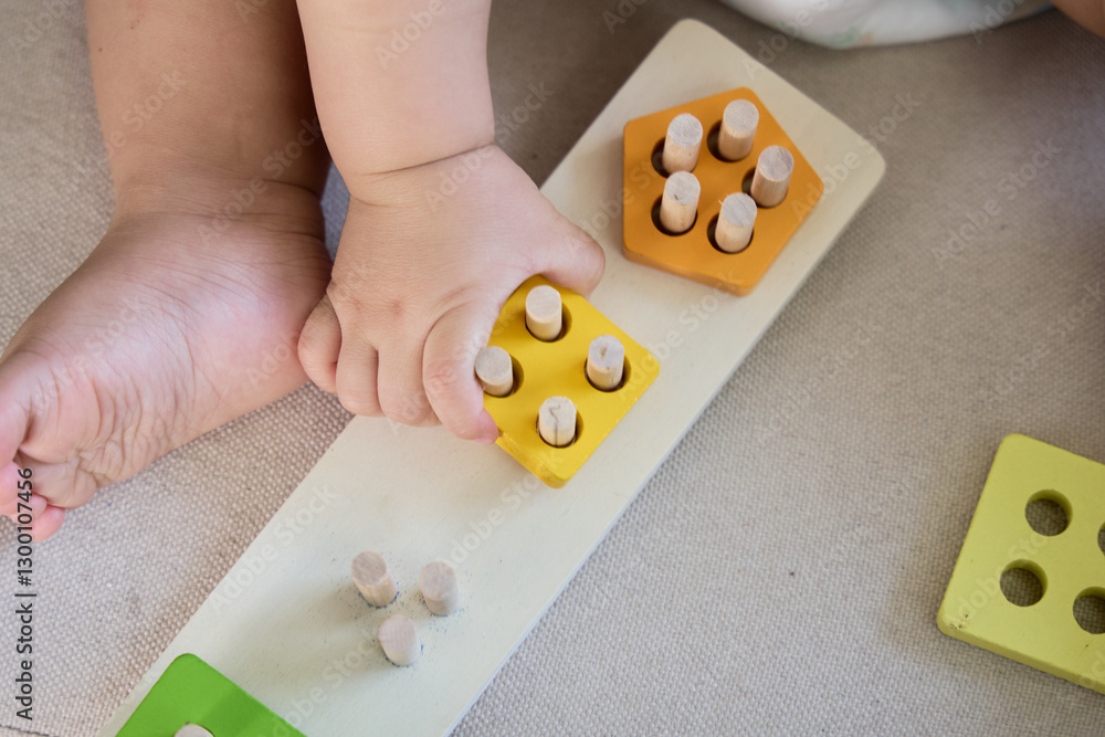 The baby is playing with a toy that has several small pieces on it, including yellow and orange ones. The baby is playing with a toy that has several small pieces on it, including yellow and orange ones.