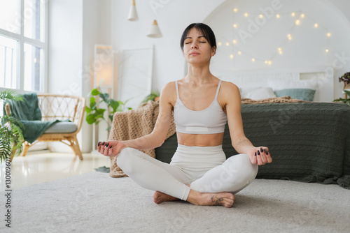 Yoga mindfulness meditation. Young healthy woman practicing yoga in living room at home. Woman sitting in lotus pose meditating smiling relaxing indoor. Girl doing breathing practice. Yoga at home