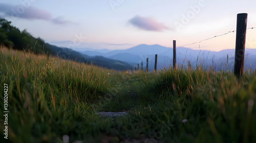 Golden Hour Landscape View Of Mountain Horizon With Green Meadow And Fence