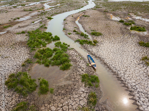 Boats are moored in a river that is drying up in the summer heat.