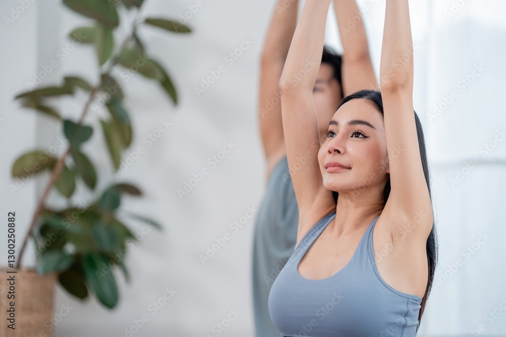 Yoga practitioners engage in a stretching routine in a bright indoor space surrounded by greenery Yoga practitioners engage in a stretching routine in a bright indoor space surrounded by greenery