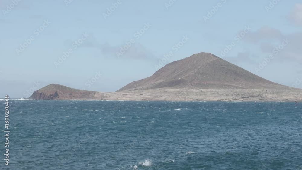 A volcanic hill by the ocean and the ocean on a sunny day in Montana Roja, El Médano, Tenerife, Canary Islands, Spain. A volcanic hill by the ocean and the ocean on a sunny day in Montana Roja, El Médano, Tenerife, Canary Islands, Spain.
